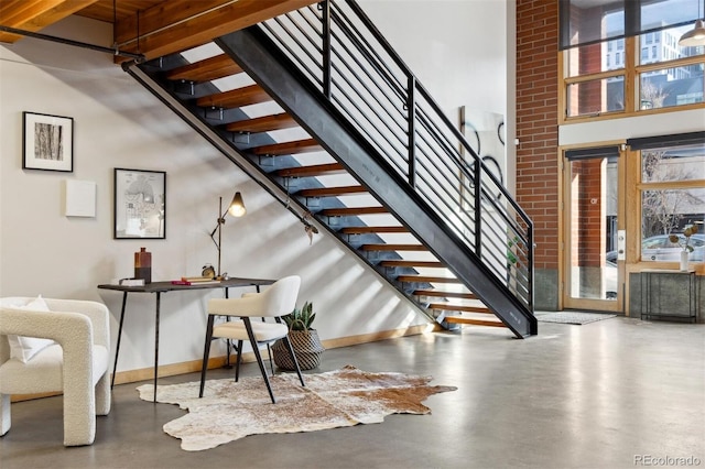 stairs with a towering ceiling and concrete floors