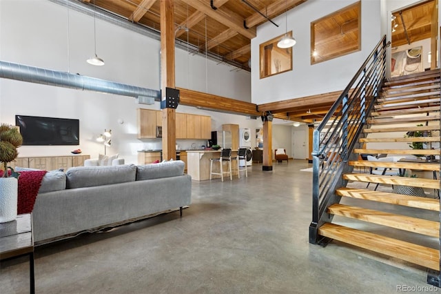 living room with wood ceiling, beamed ceiling, and a high ceiling