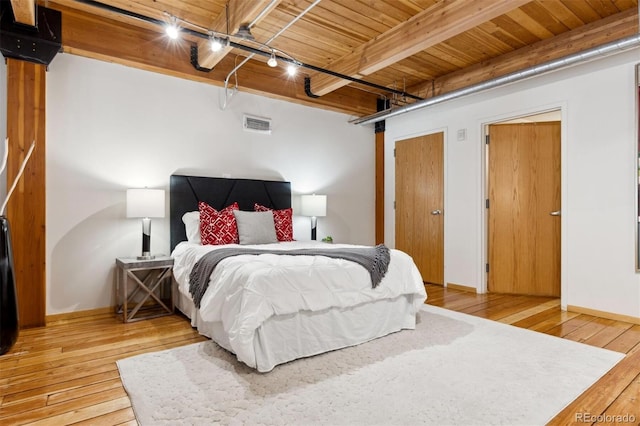 bedroom with wood ceiling, track lighting, beam ceiling, and light hardwood / wood-style floors