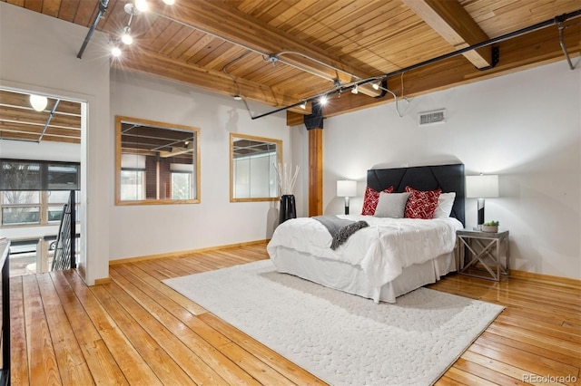 bedroom with beamed ceiling, rail lighting, hardwood / wood-style floors, and wood ceiling