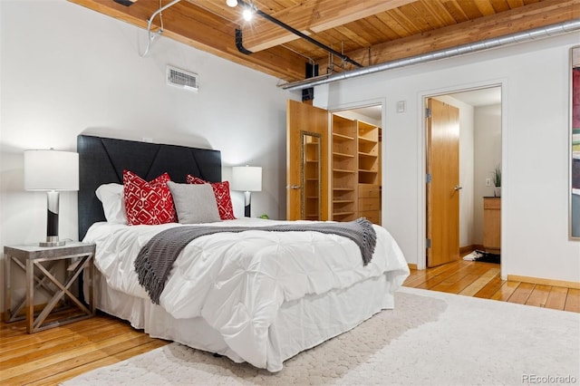 bedroom featuring wood ceiling, a walk in closet, wood-type flooring, and beamed ceiling