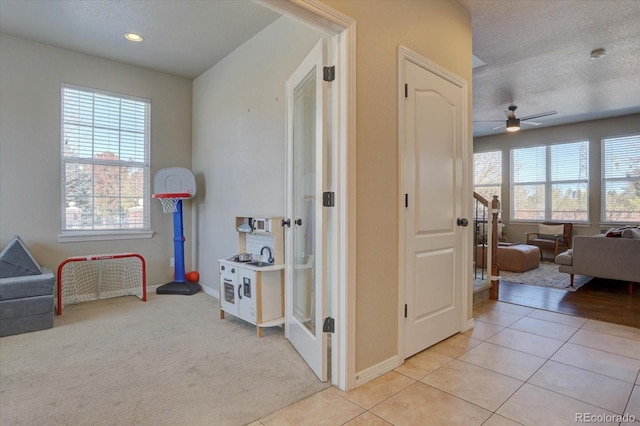 rec room featuring ceiling fan, light colored carpet, and a textured ceiling