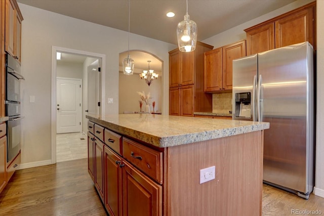 kitchen with decorative light fixtures, a kitchen island, light hardwood / wood-style floors, and stainless steel refrigerator with ice dispenser