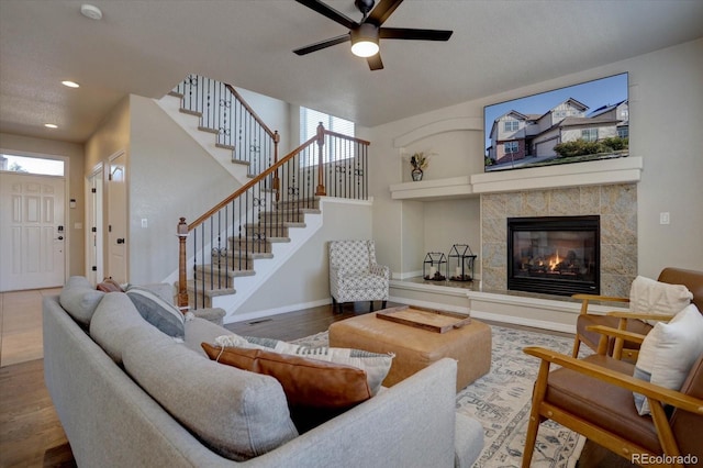 living room featuring hardwood / wood-style floors, ceiling fan, a wealth of natural light, and a tiled fireplace