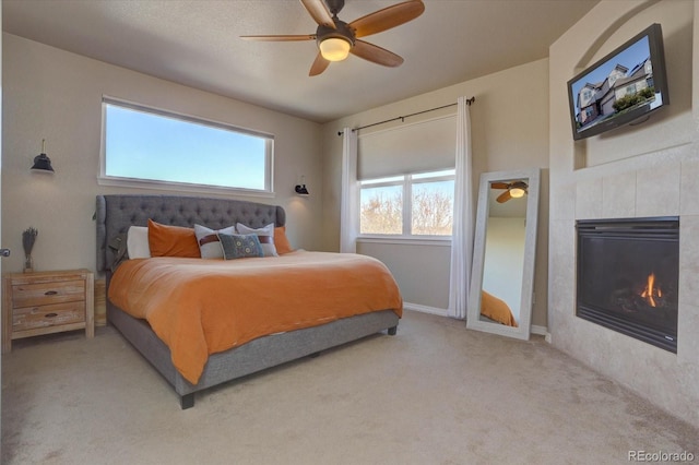 bedroom with a tile fireplace, ceiling fan, and carpet