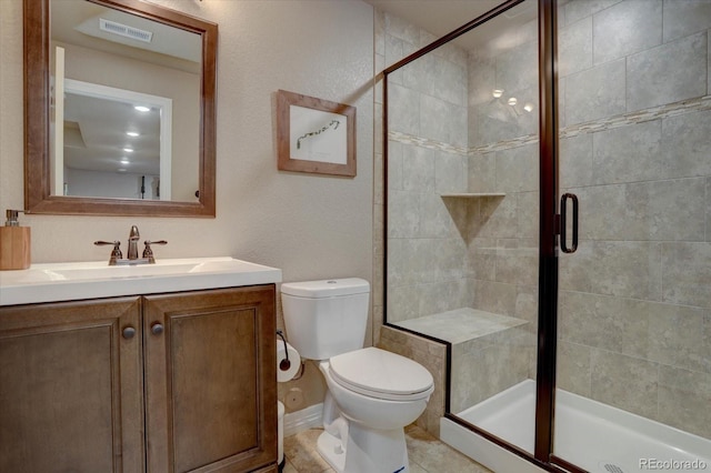 bathroom with tile patterned floors, vanity, a shower with shower door, and toilet