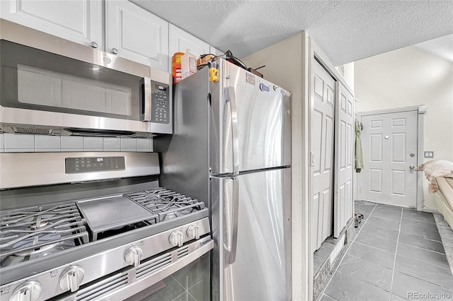 8701 Huron St Unit 211, Thornton, CO 80260 - kitchen with appliances with stainless steel finishes, white cabinetry, and a textured ceiling