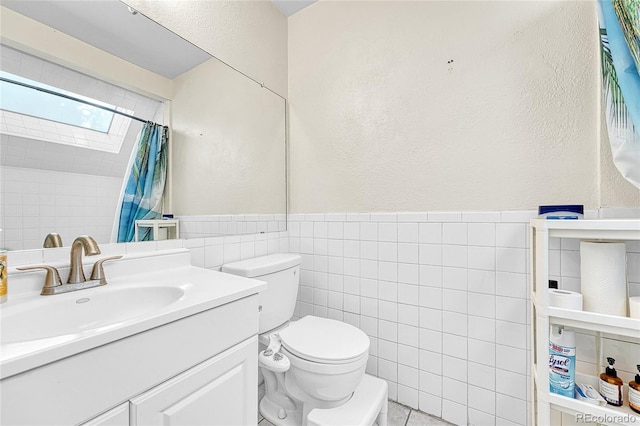 8701 Huron St Unit 211, Thornton, CO 80260 - bathroom featuring tile walls, a skylight, a textured wall, toilet, and vanity