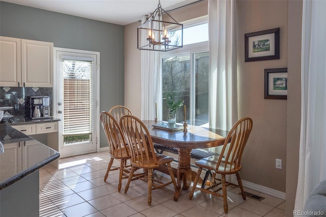 tiled dining room featuring an inviting chandelier and plenty of natural light