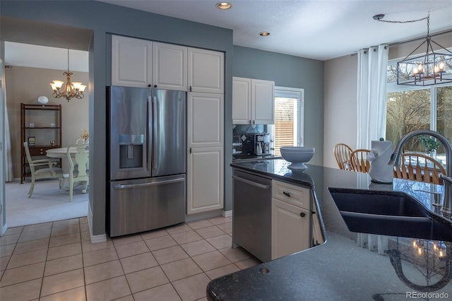 kitchen with light tile patterned flooring, sink, an inviting chandelier, stainless steel appliances, and white cabinets