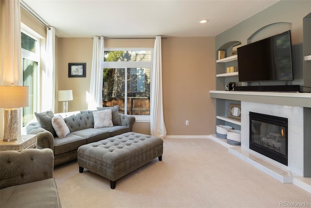 living room featuring built in features, a fireplace, and light carpet