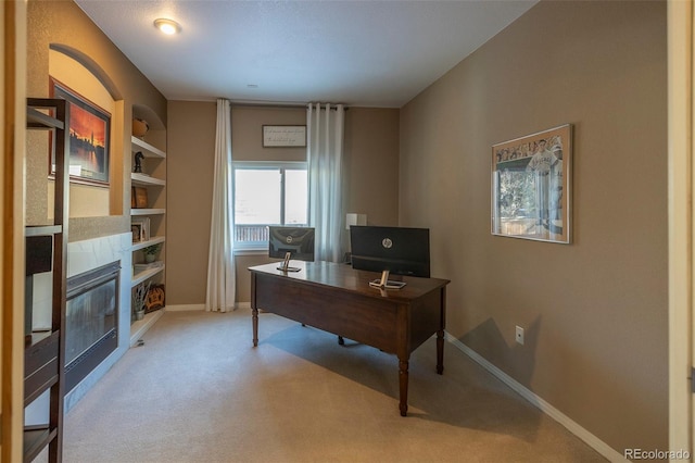 office space featuring built in shelves, light colored carpet, and a tile fireplace