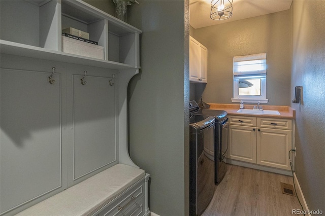 laundry room with cabinets, sink, light hardwood / wood-style flooring, and washing machine and clothes dryer