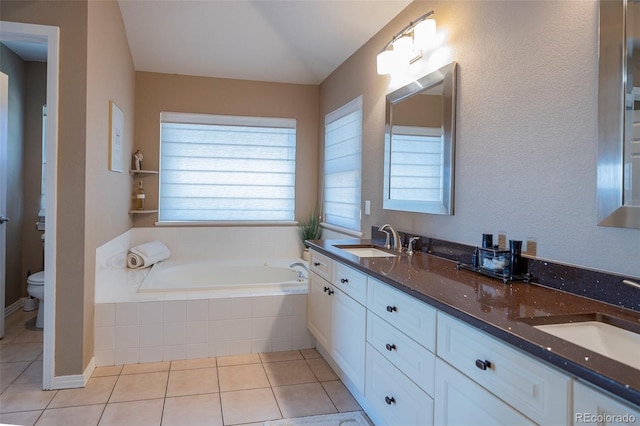 bathroom with vanity, tiled tub, tile patterned floors, and toilet