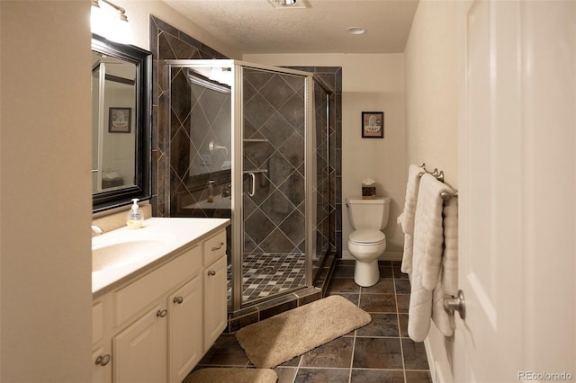 bathroom with vanity, a textured ceiling, a shower with shower door, and toilet