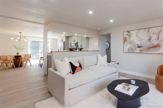 living area with recessed lighting, baseboards, a notable chandelier, and light wood finished floors