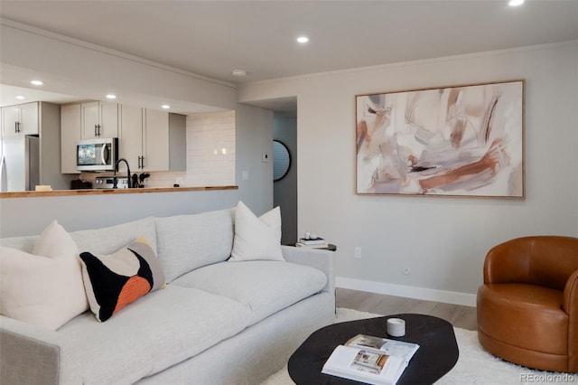 living room with recessed lighting, light wood-type flooring, baseboards, and ornamental molding