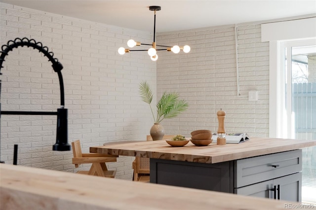 unfurnished dining area featuring a notable chandelier and brick wall