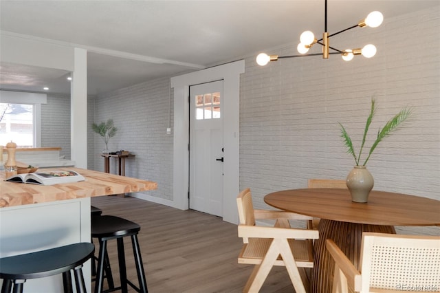 dining area featuring wood finished floors, brick wall, and a chandelier