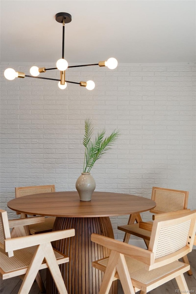 dining room with a notable chandelier and brick wall