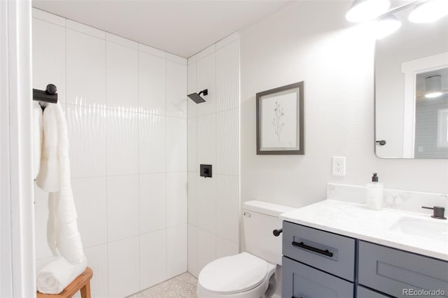 full bath featuring tiled shower, toilet, and vanity