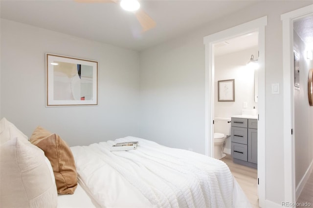 bedroom with a ceiling fan, light wood-style floors, baseboards, and ensuite bathroom