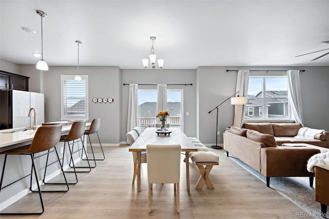 dining space with sink, light wood-type flooring, and a chandelier