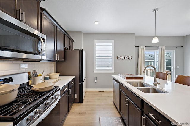 kitchen with a wealth of natural light, appliances with stainless steel finishes, decorative light fixtures, and sink