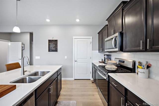 kitchen featuring light hardwood / wood-style floors, sink, decorative backsplash, appliances with stainless steel finishes, and decorative light fixtures