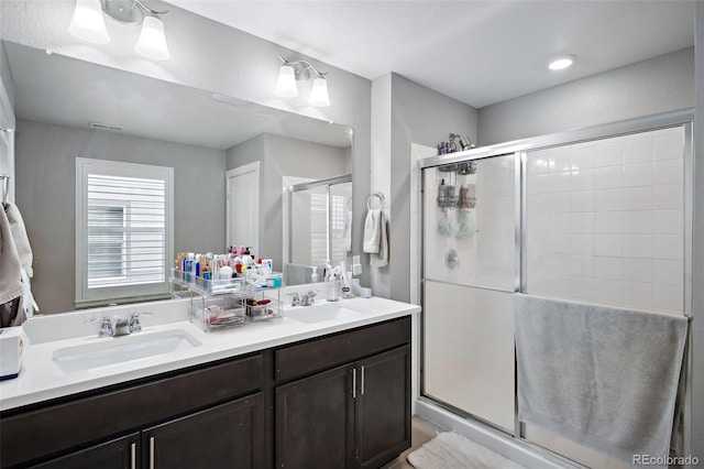 bathroom featuring a shower with door and vanity