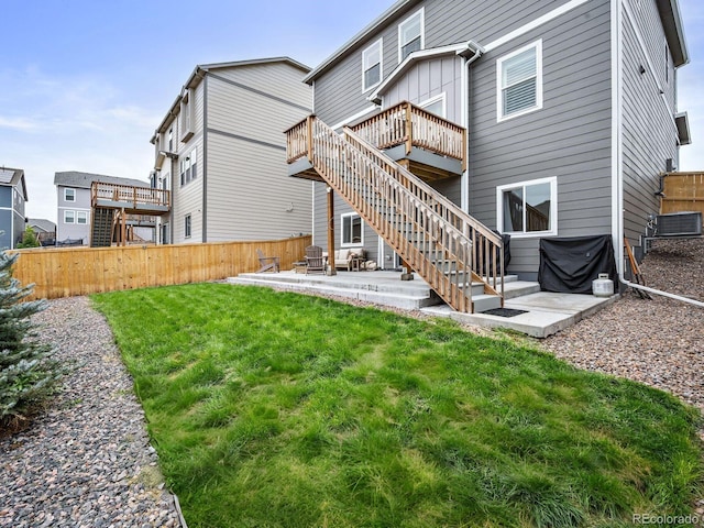 rear view of house with a wooden deck, a lawn, and a patio