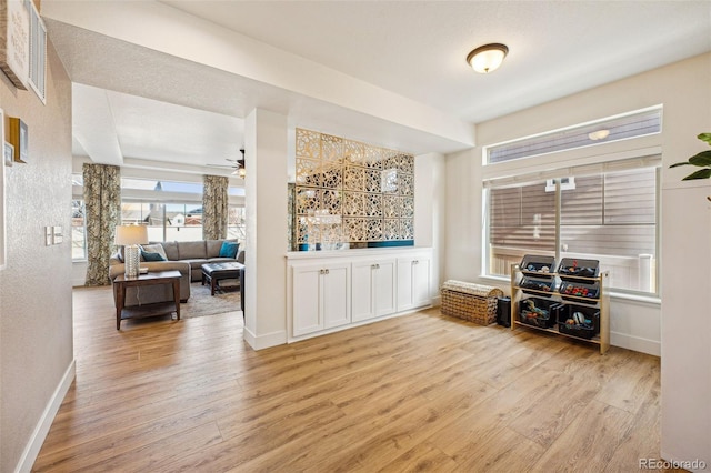 interior space featuring visible vents, wood finished floors, baseboards, ceiling fan, and a textured wall