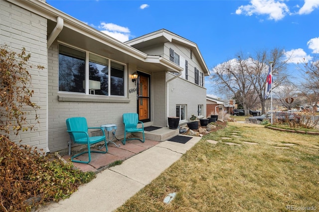 back of property with a yard and brick siding