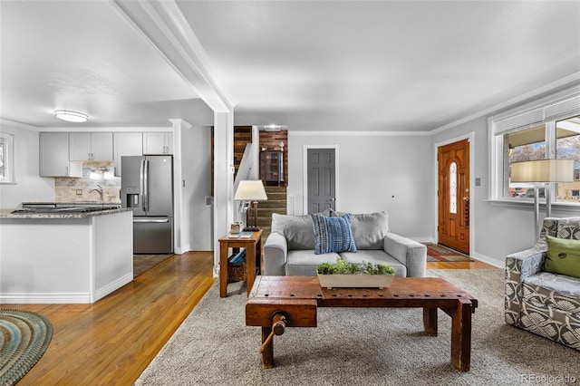 living room with baseboards, wood finished floors, and crown molding