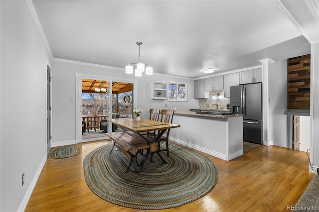 dining space with a chandelier, baseboards, light wood-style flooring, and crown molding