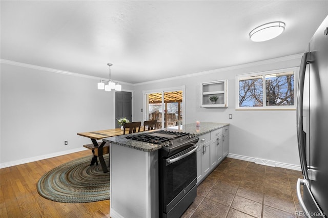 kitchen featuring visible vents, range with gas cooktop, baseboards, a peninsula, and freestanding refrigerator