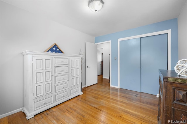 bedroom with a closet, baseboards, and light wood finished floors