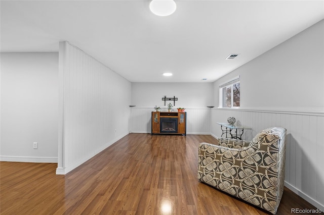 unfurnished room featuring visible vents, wainscoting, wood finished floors, and a fireplace