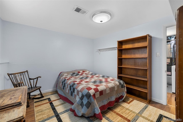 bedroom featuring visible vents, baseboards, and wood finished floors