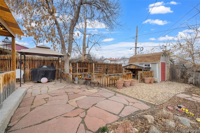 view of patio / terrace featuring a gazebo, a fenced backyard, an outbuilding, area for grilling, and a storage unit