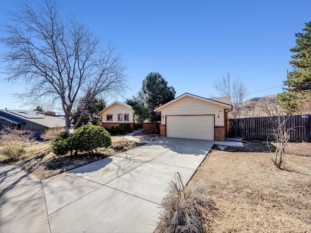 view of front of house featuring brick siding, an attached garage, concrete driveway, and fence