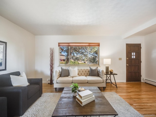 living area featuring baseboards, baseboard heating, and wood finished floors