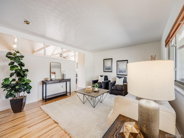 living room featuring wood finished floors, baseboards, and ceiling fan