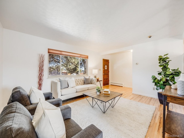 living area featuring a baseboard heating unit, light wood-style flooring, and baseboards