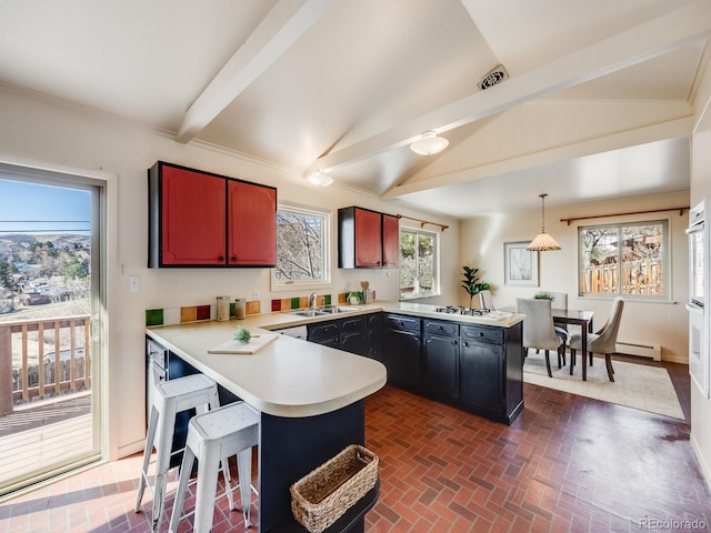 kitchen with visible vents, light countertops, a peninsula, brick floor, and a sink