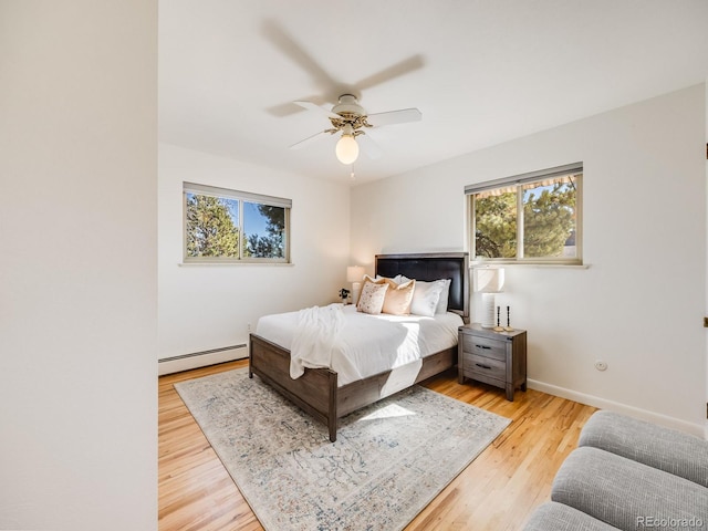 bedroom with a baseboard radiator, baseboards, ceiling fan, and light wood finished floors