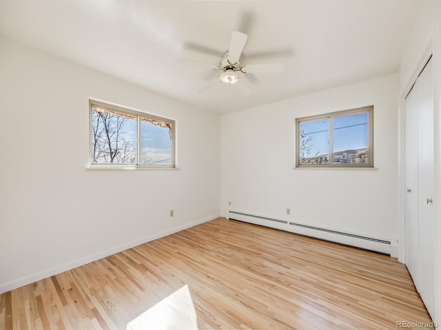 unfurnished bedroom with light wood-style flooring, a ceiling fan, a closet, baseboards, and baseboard heating