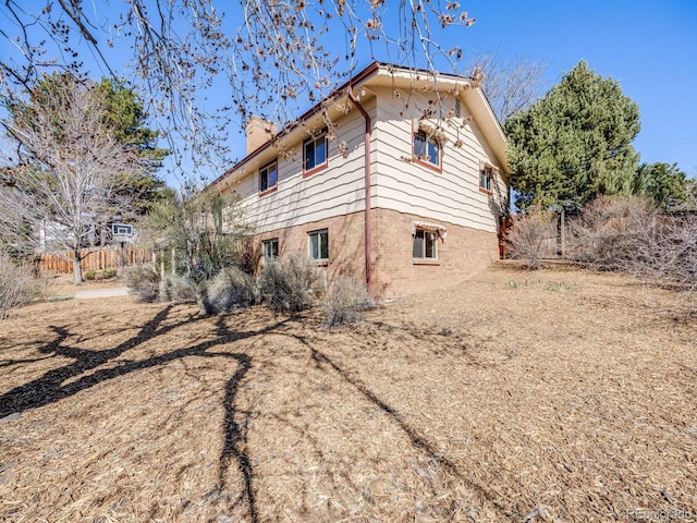 view of side of property featuring a chimney and fence