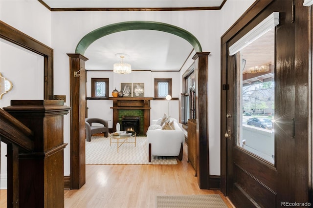 1220 S Vine St, Denver, CO 80210 - entrance foyer featuring light wood-type flooring, crown molding, arched walkways, a chandelier, and a warm lit fireplace
