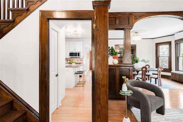 1220 S Vine St, Denver, CO 80210 - corridor with radiator heating unit, ornate columns, light wood finished floors, stairway, and a chandelier